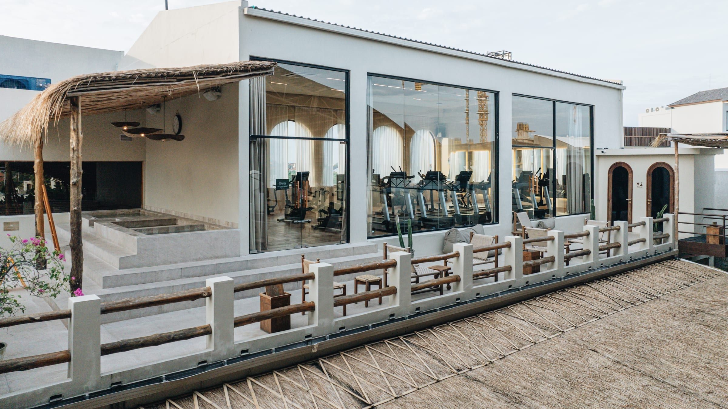 Gym with treadmills behind floor-to-ceiling windows on the clubhouse terrace
