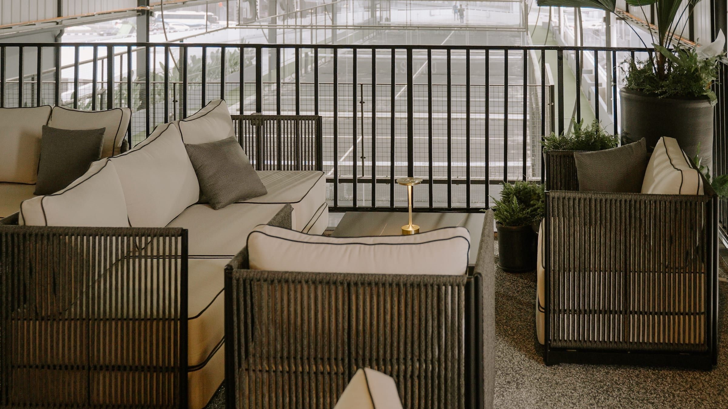 Wicker sofas with cream cushions in a lounge beside the courts