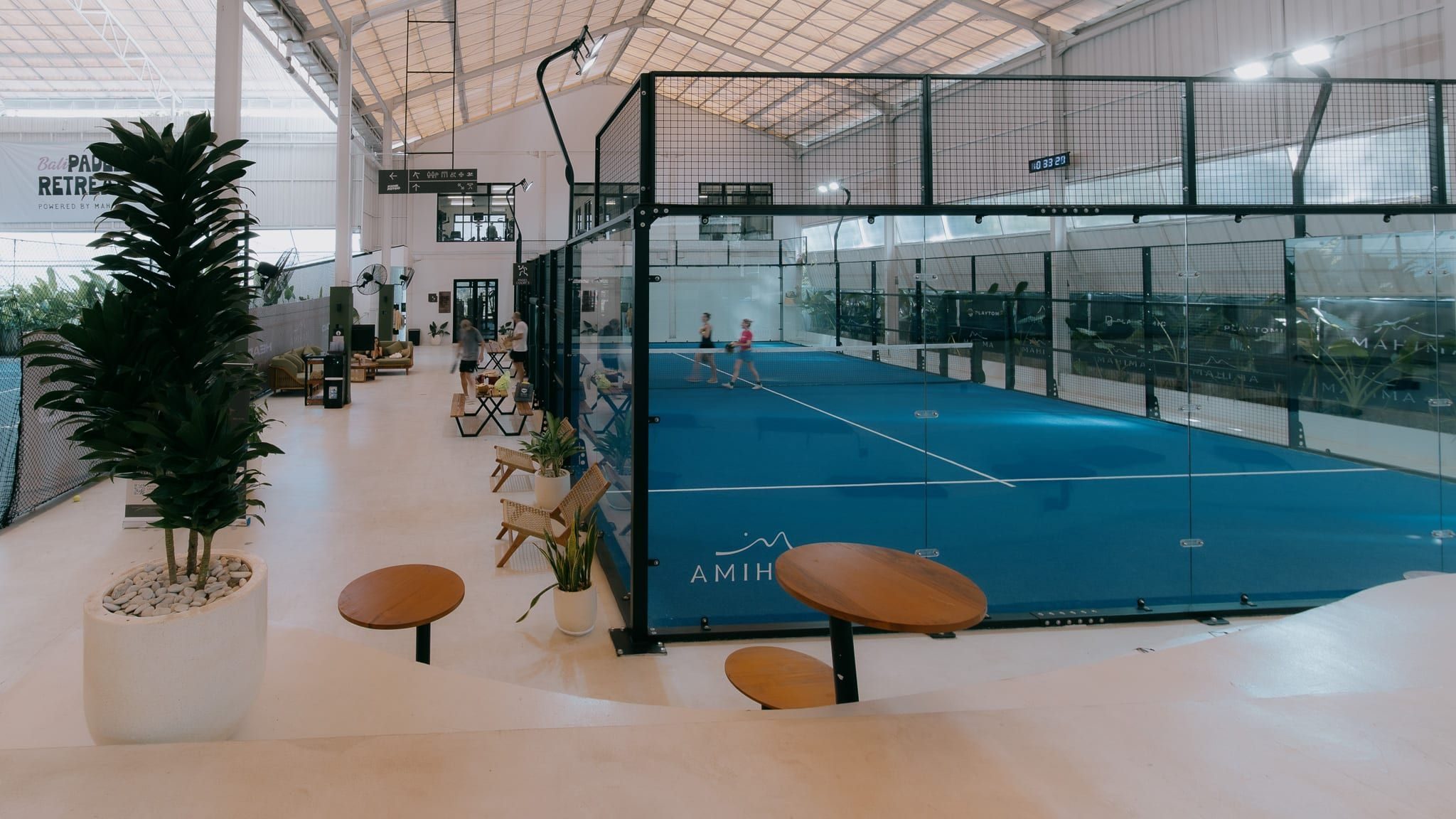 Seating area beside a blue indoor padel court