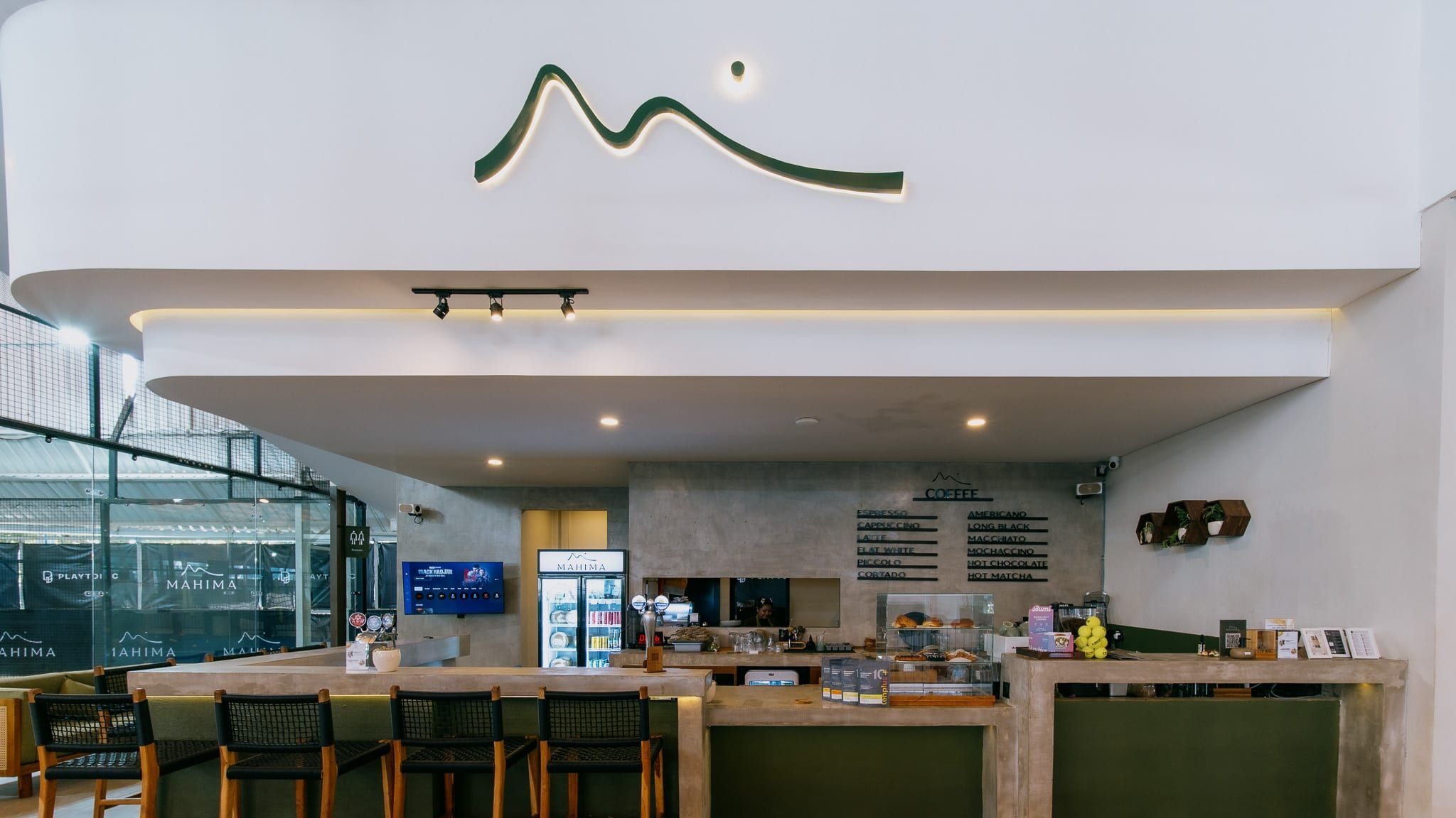 Café counter and bar stools under the Mahima logo