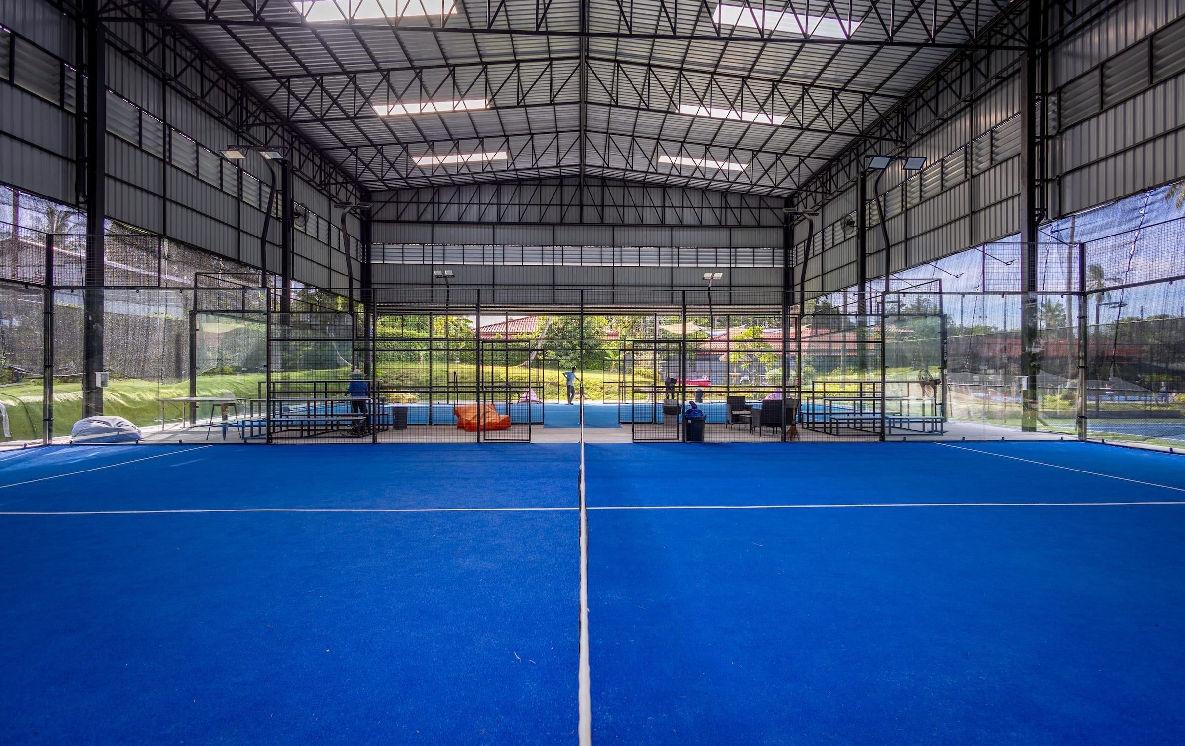 Covered blue padel courts under a high steel roof