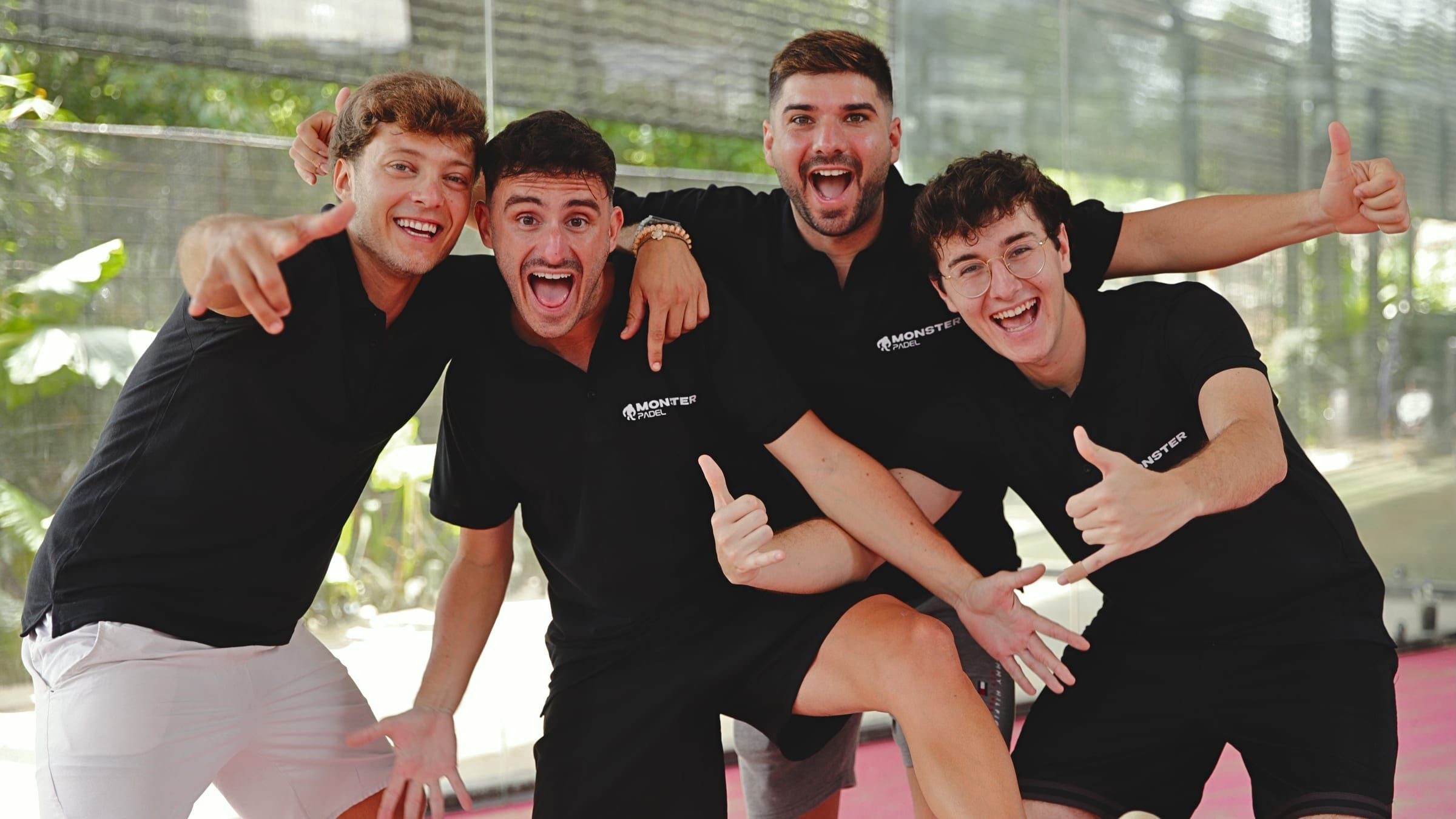Four coaches in black Monster Padel shirts cheering for the camera